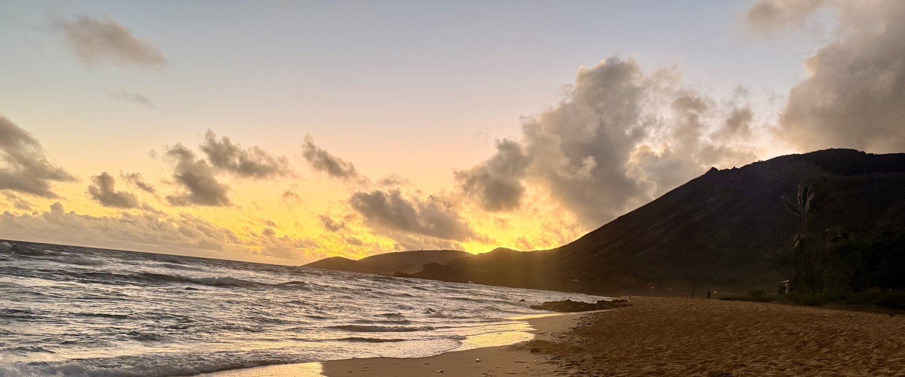 A quiet beach at golden hour with footprints along the shore
