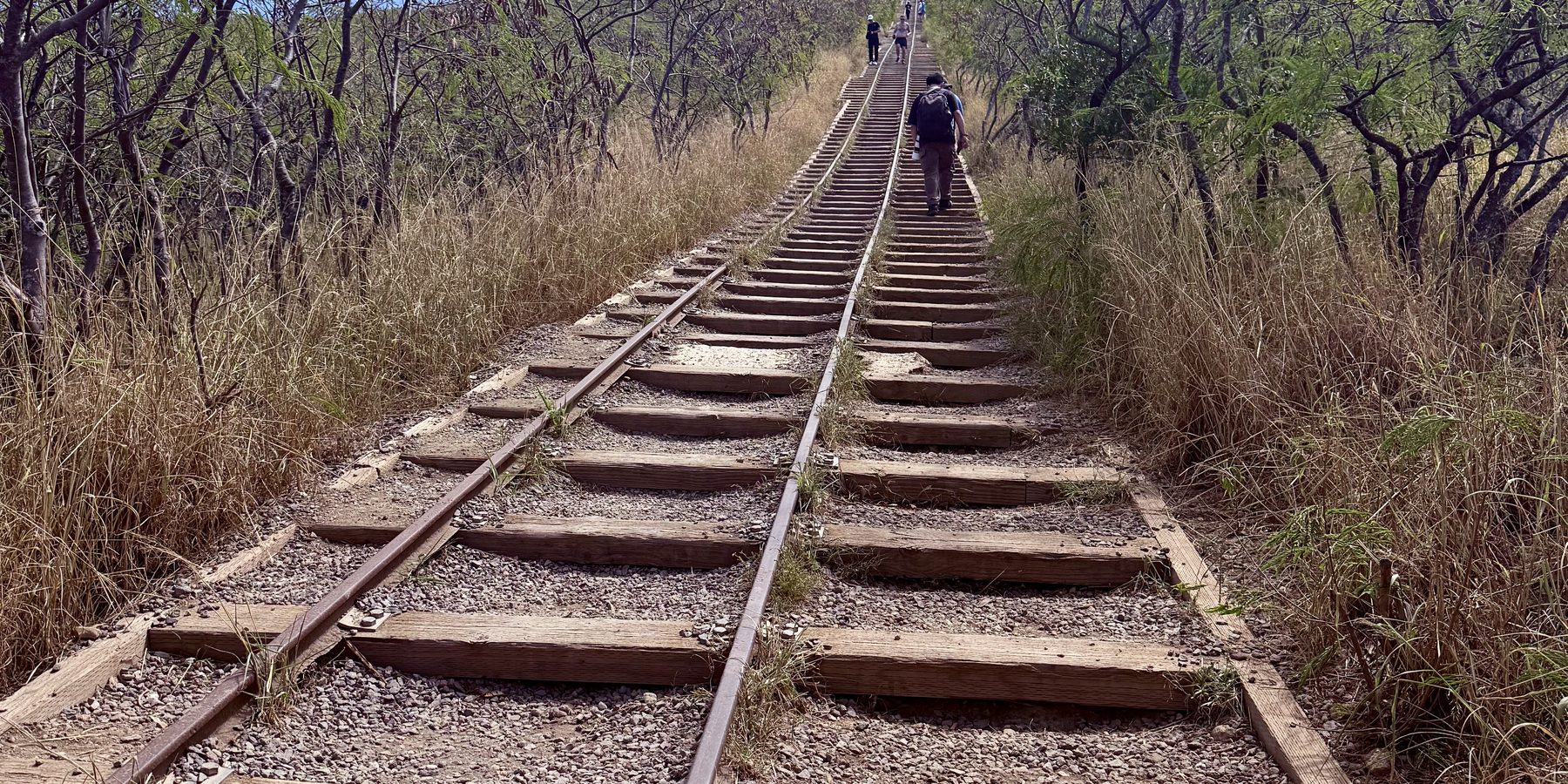 A railway track climbing a hillside with people walking upward